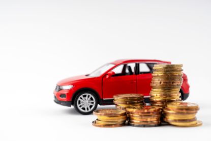 Image of a red car and a stack of coins on a white background.