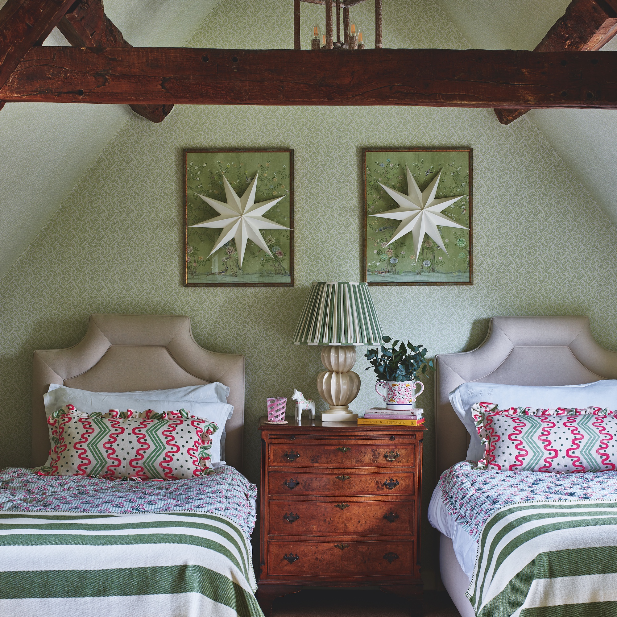 green loft bedroom with wooden beams and twin beds with upholstered headboards and green strip throws