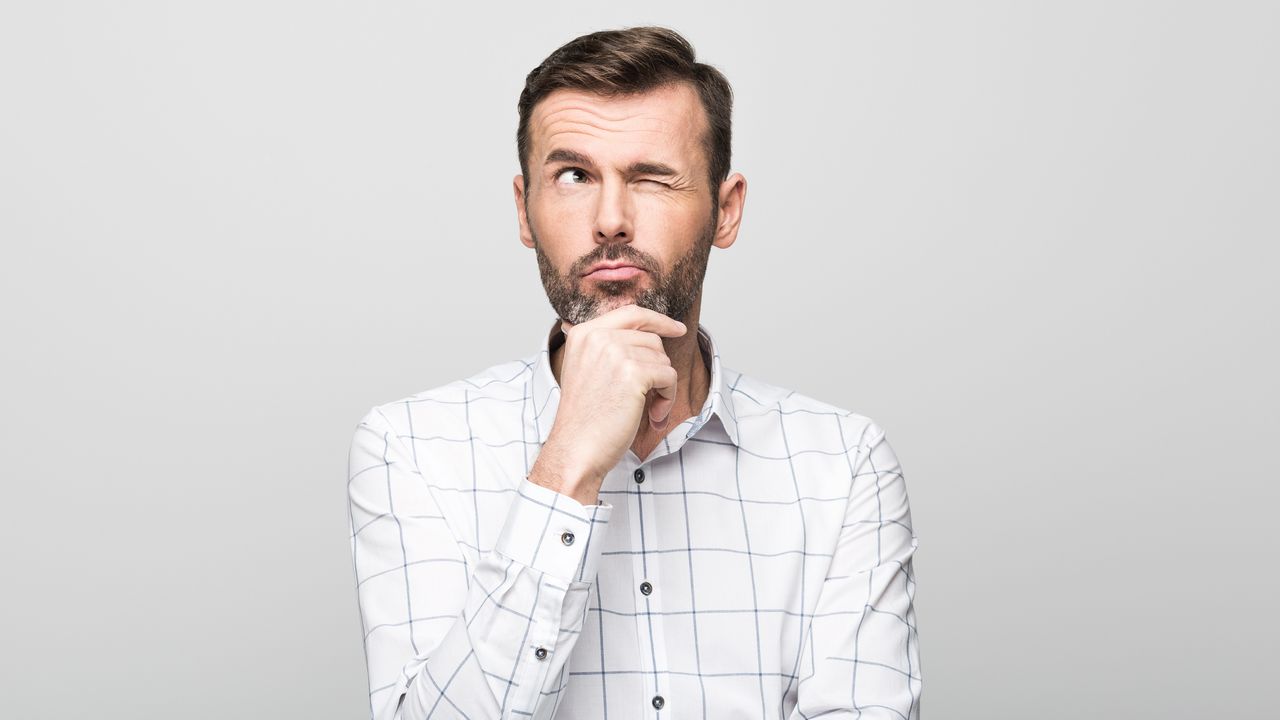 A man has a thoughtful look on his face as he looks into space.