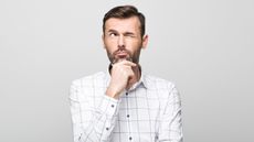 A man has a thoughtful look on his face as he looks into space.