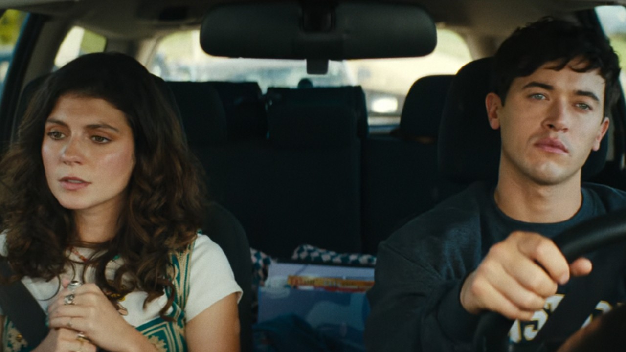 Poppy sitting in the passenger seat and Alex driving.