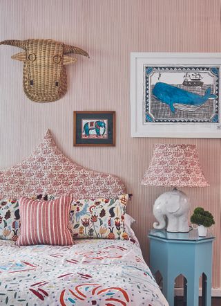 A bohemian child's bedroom with a sculptural pink and white headboard and an elephant shaped bedside lamp