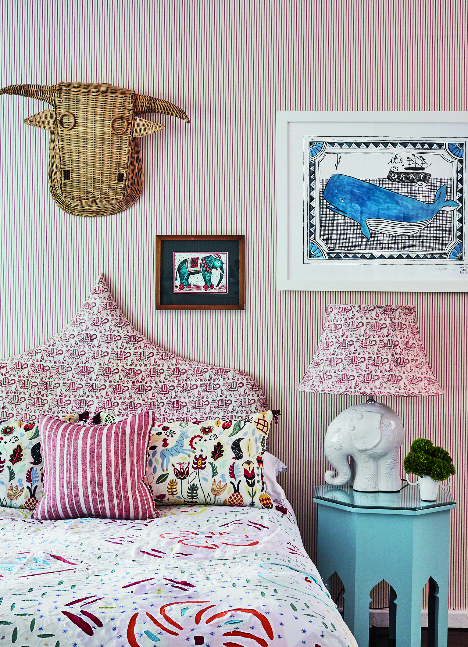 A bohemian child's bedroom with a sculptural pink and white headboard and an elephant shaped bedside lamp