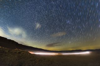 The image shows a colorful star trail captured from inside Ramon Crater, the world's largest "erosion cirque," located in Israel's Negev Desert.