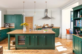 green kitchen with cabinets and island with wooden worktops