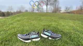 Hoka Cielo X1 running shoes on grass in front of Olympic rings
