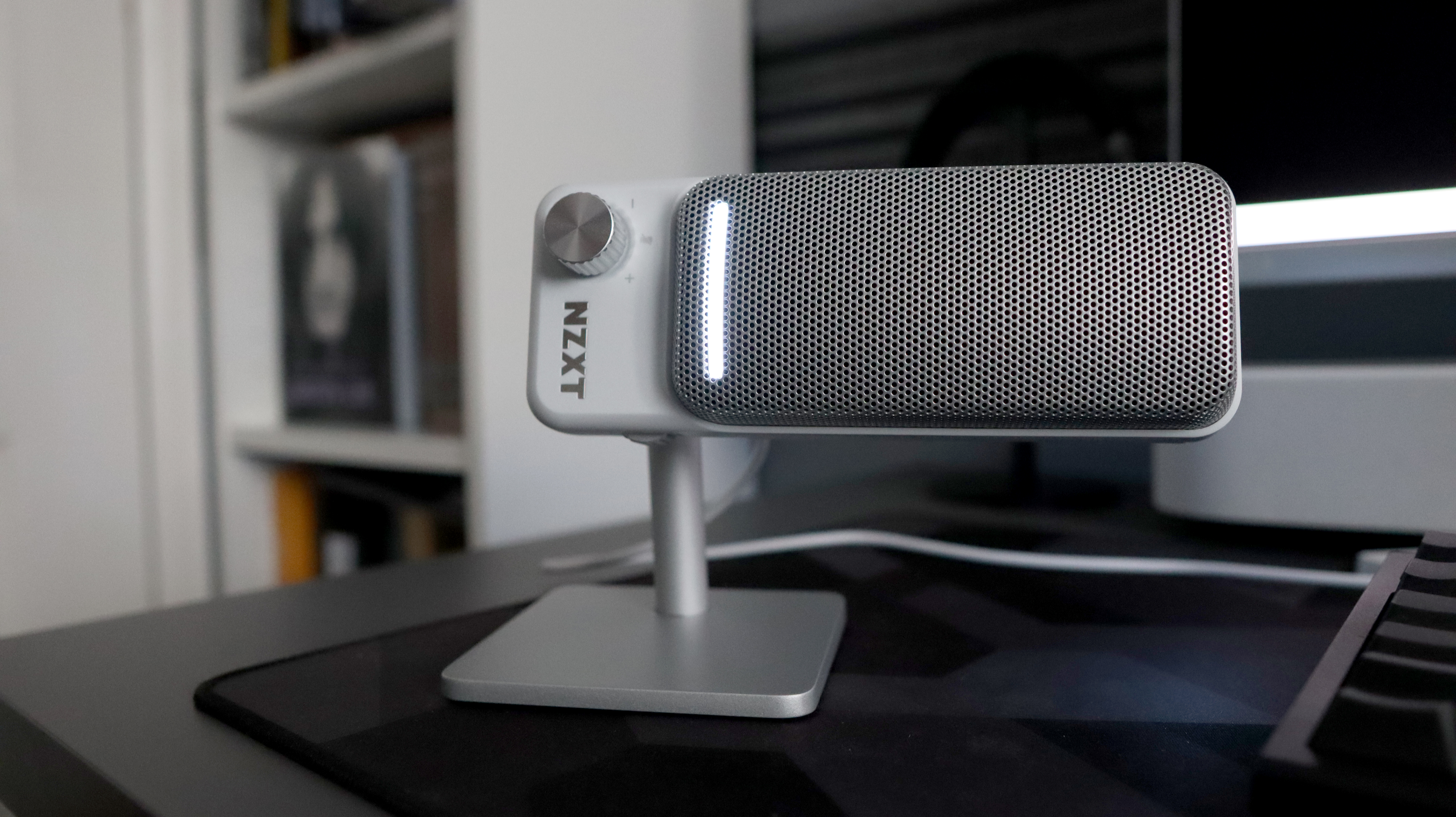 An NZXT Capsule Elite microphone set up on a desk with lighting enabled.