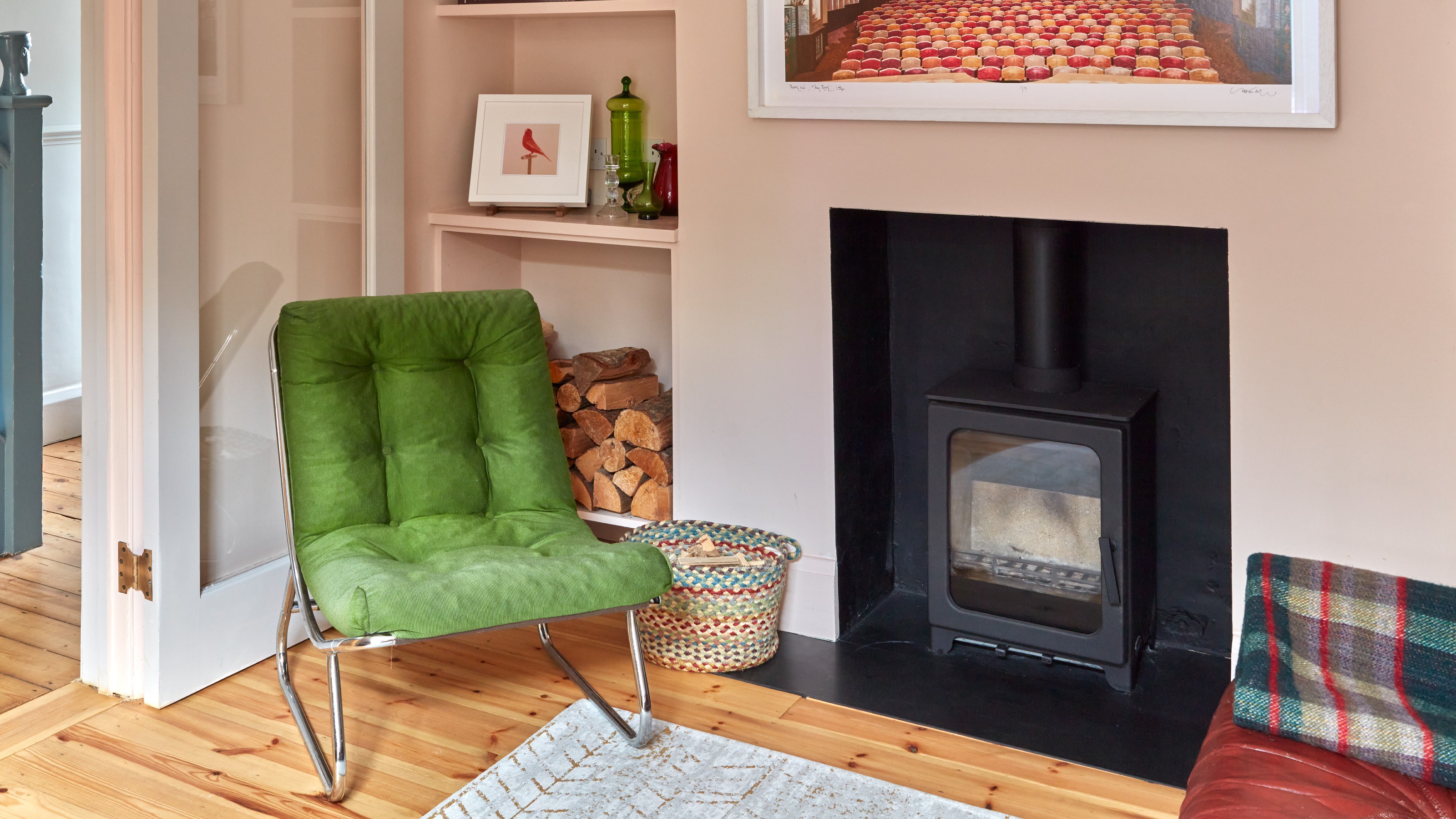 A soft pink-painted living room with a green corduroy-upholstered lounge chair with a chrome frame