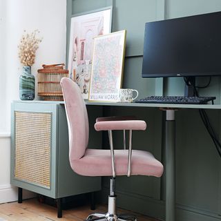Green panelled wall with built in desk and cabinet, computer desktop and pink office chair