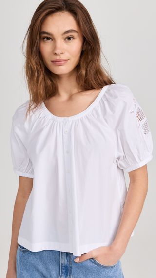 Model is wearing a white cotton top with puff sleeves