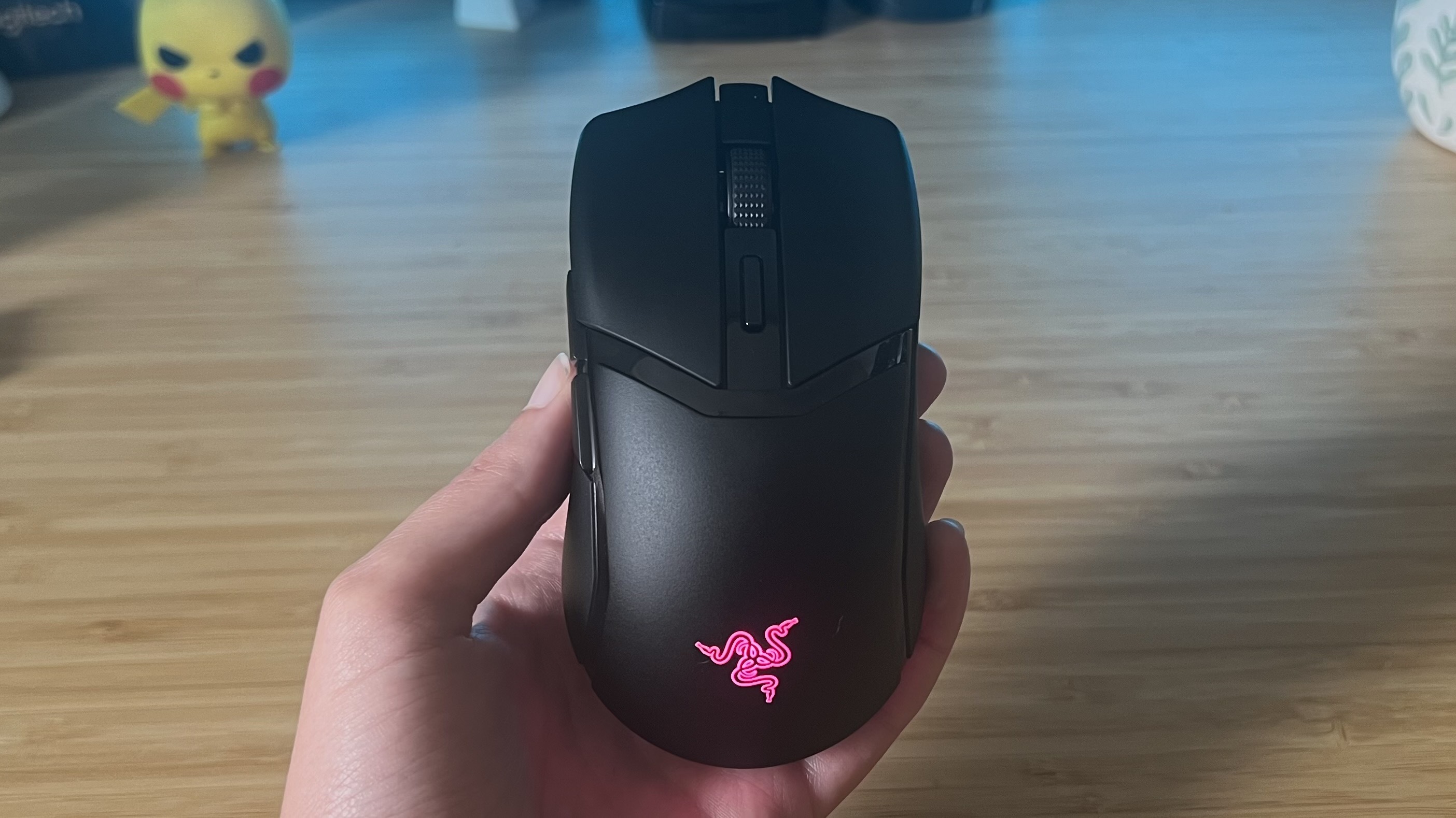 Razer Cobra Hyperspeed gaming mouse being held above a gaming desk setup