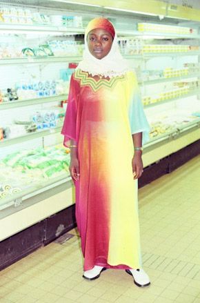 African woman wearing traditional clothes near fridges in supermarket
