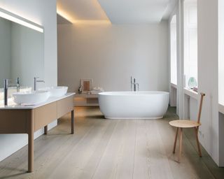 Minimalist bathroom with light wooden flooring, bath, sink, wooden stool