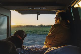 Dog sitting next to female owner in back of camper van