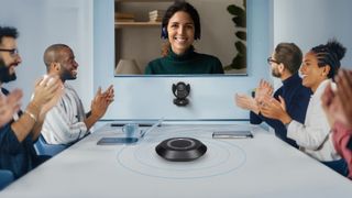 The new AVer camera and speaker videoconferencing solution being used in a medium-sized conference room with smiling people.