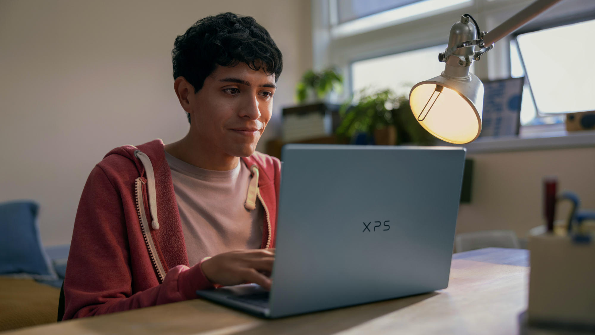 Dell XPS 13 laptop being used by a student on a desk with a lamp near the screen