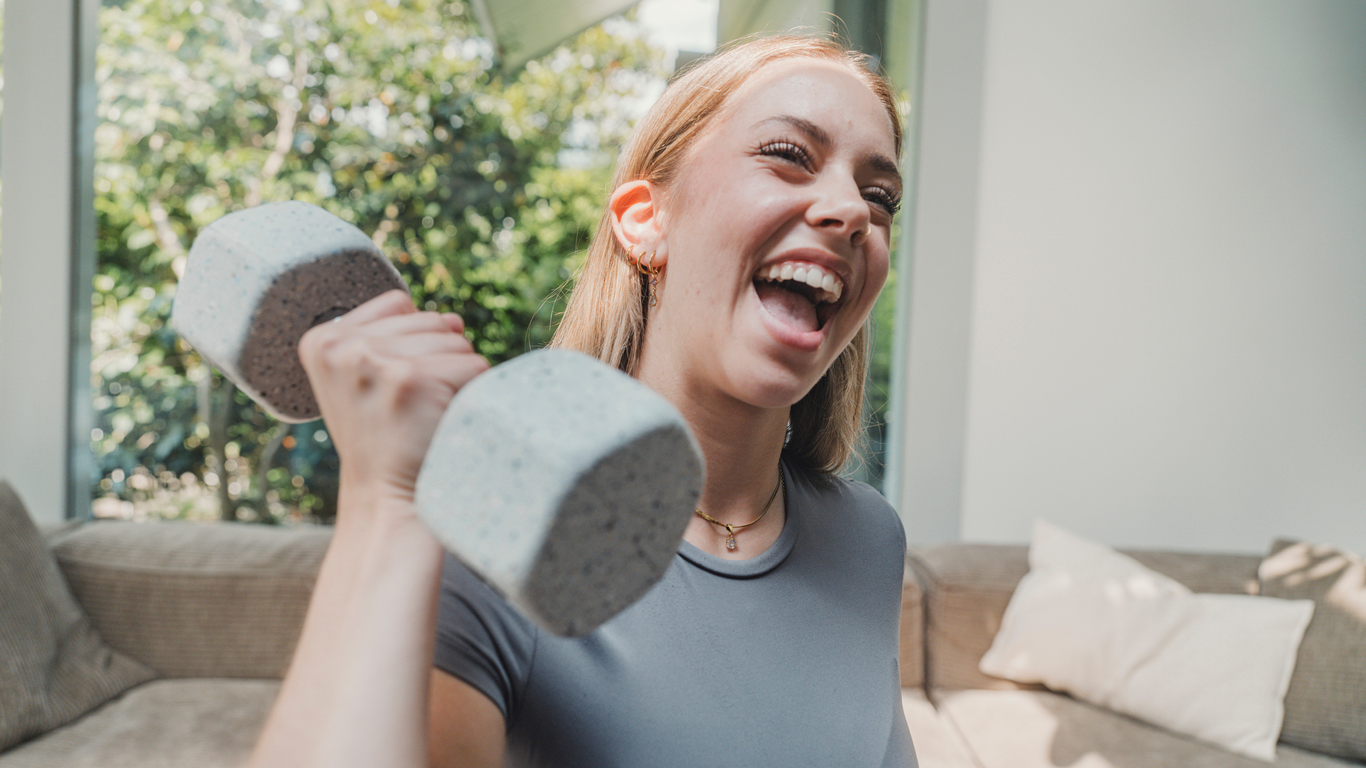 Smiling woman holds dumbbell in domestic setting