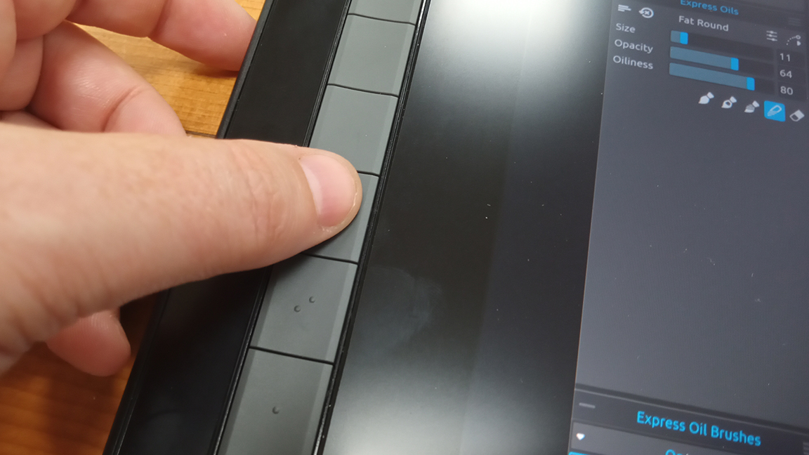 XP-Pen Artist 16 (2nd gen); a photo of a thumb pressing a button on a tablet