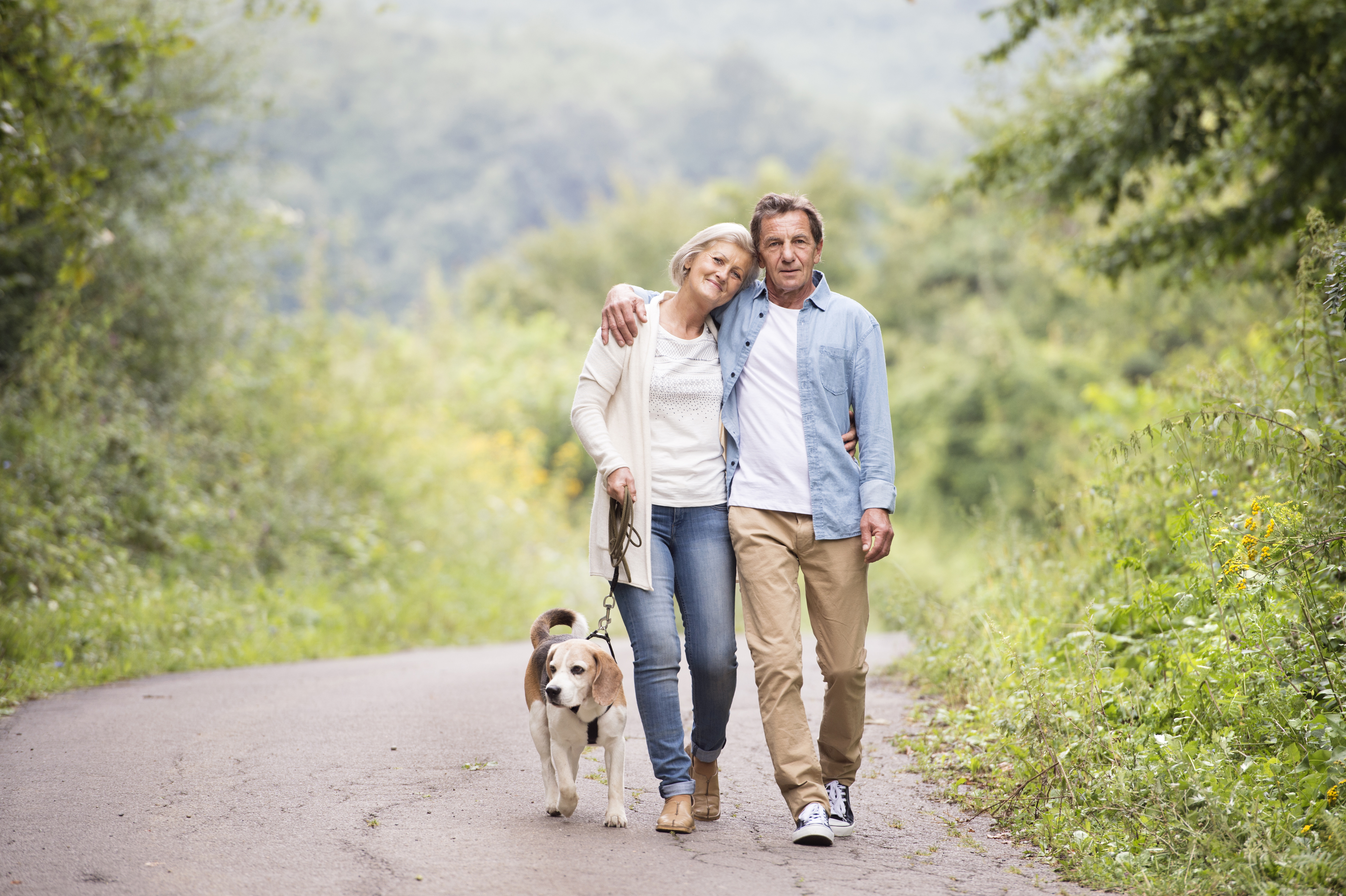 A mature couple and their dog on a walk.