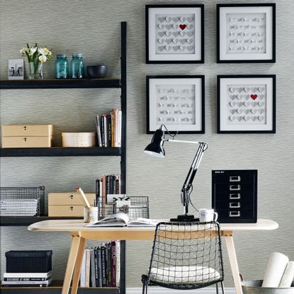 a monochrome scheme with touches of red a group of four pictures on the wall a shelving unit behind a desk and chair