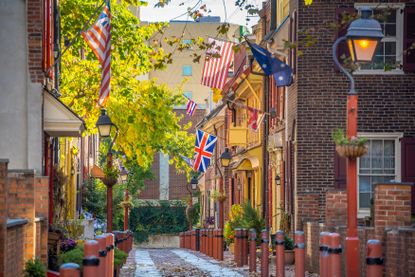 A quaint street in Philadelphia, Pennsylvania with historic buildings, street lamps, and flags