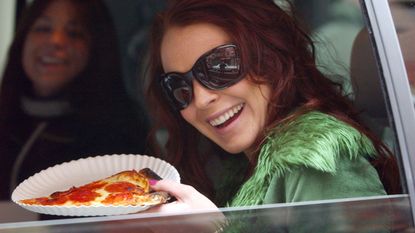 Woman holding up slice of pizza