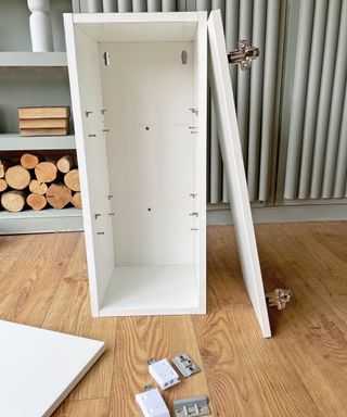 A slim kitchen cabinet being assembled on a wooden floor