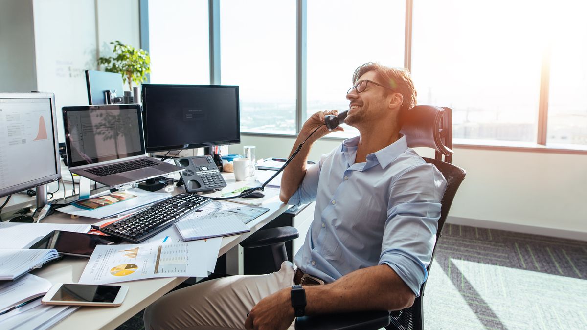 Smiling man working in office with PC monitor in background