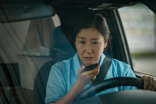 a woman sitting in a car talks into a cell phone