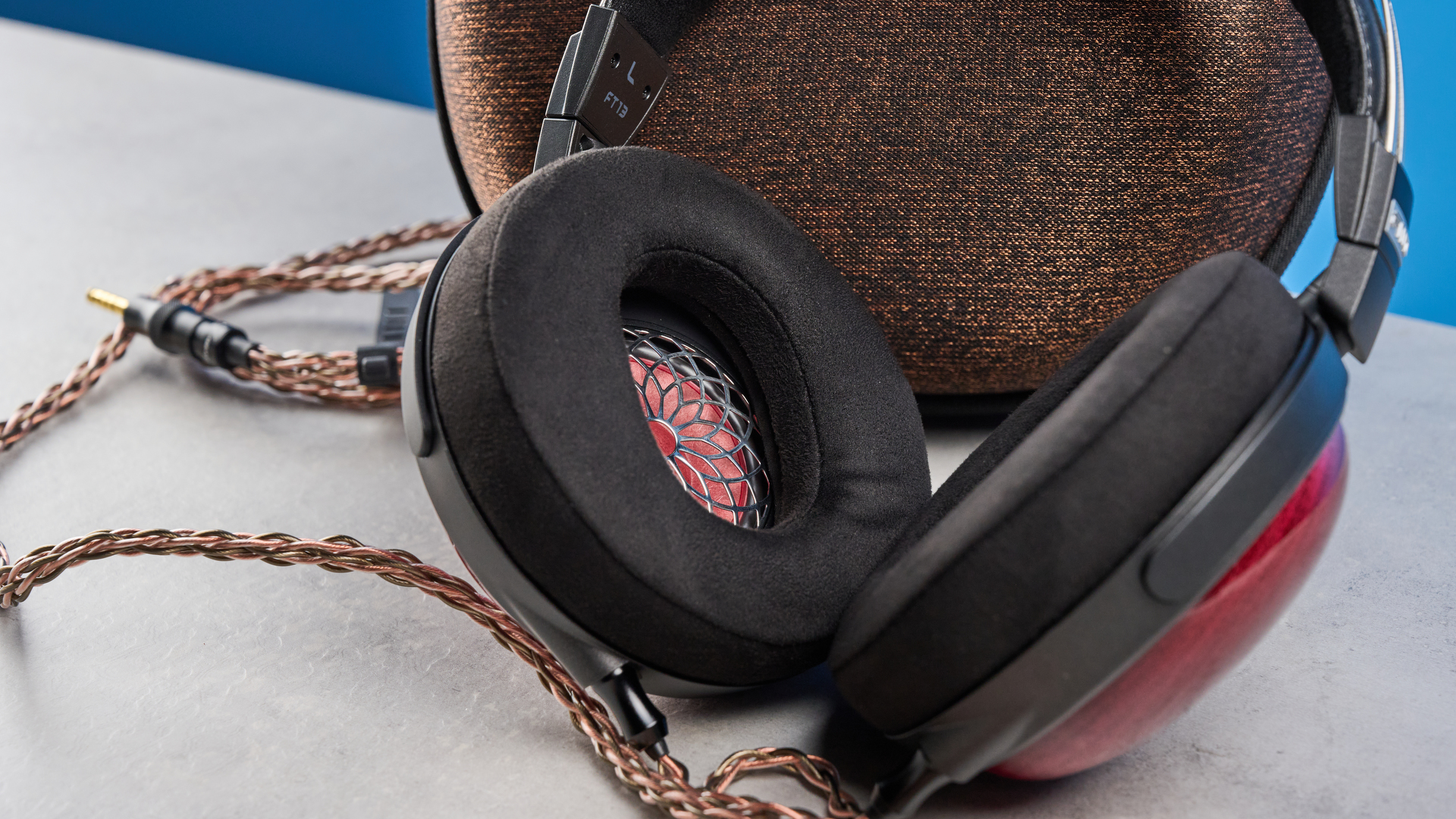 the fiio ft13 wired headphones with wood cups and copper cable photographed against a blue background