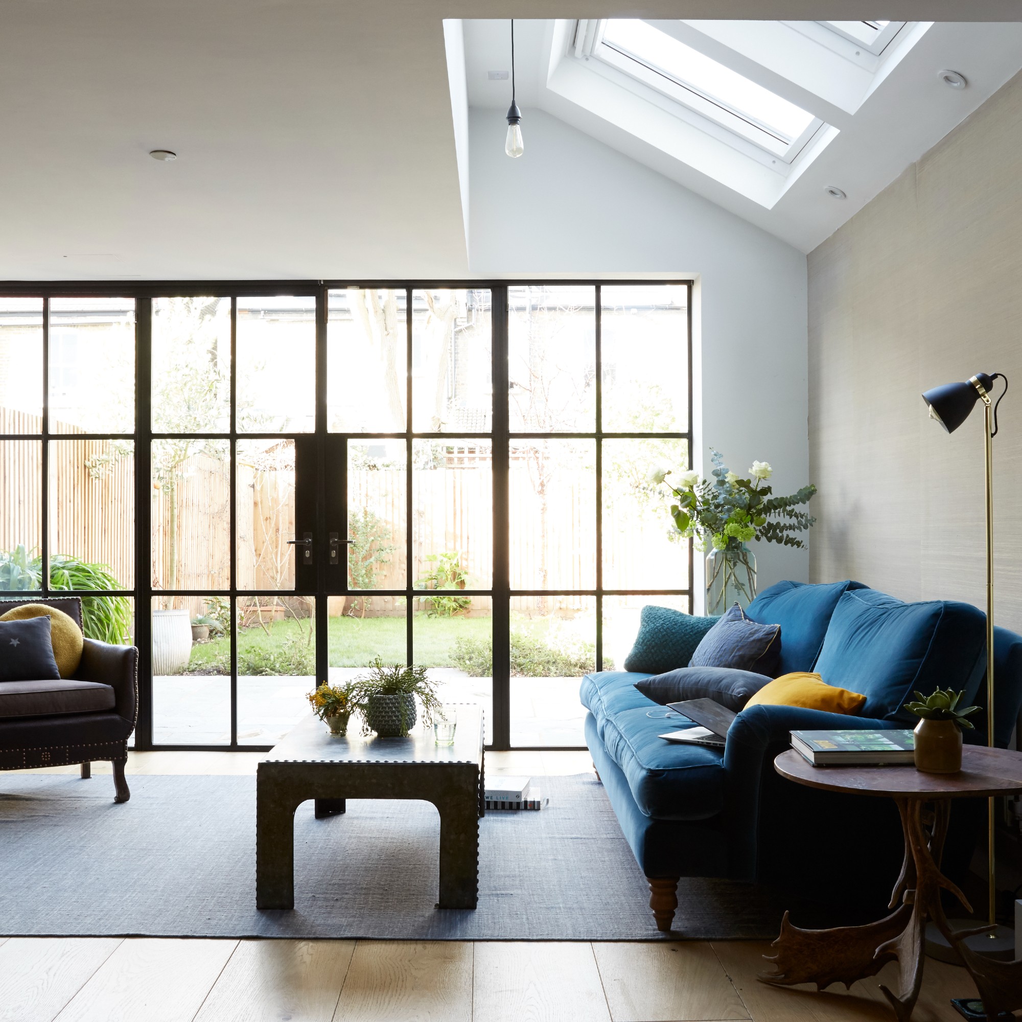 An open-plan living room with a blue velvet sofa and a sky light