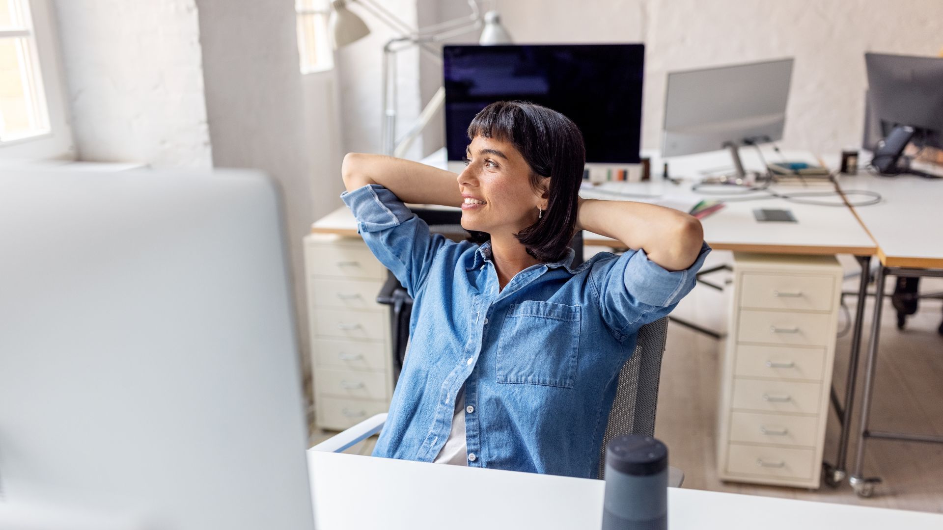 Woman sitting comfortably in a chair behind desk