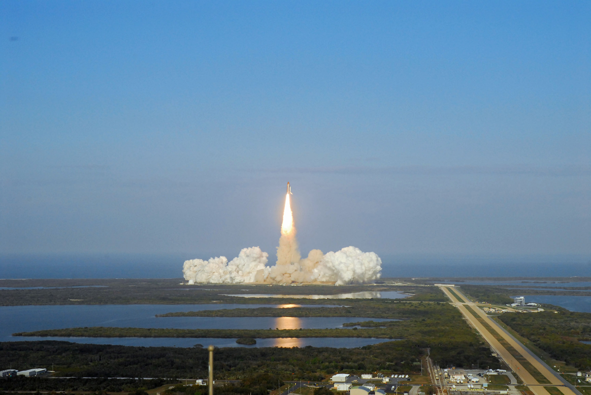 Space shuttle Discovery lifts off Launch Pad 39A atop twin columns of fire, creating rolling clouds of smoke and steam in its track. Launch of the STS-133 mission was at 4:53 p.m. EST on Feb. 24, 2011 as seen from the roof of NASA&#039;s 52-story Vehicle Assem