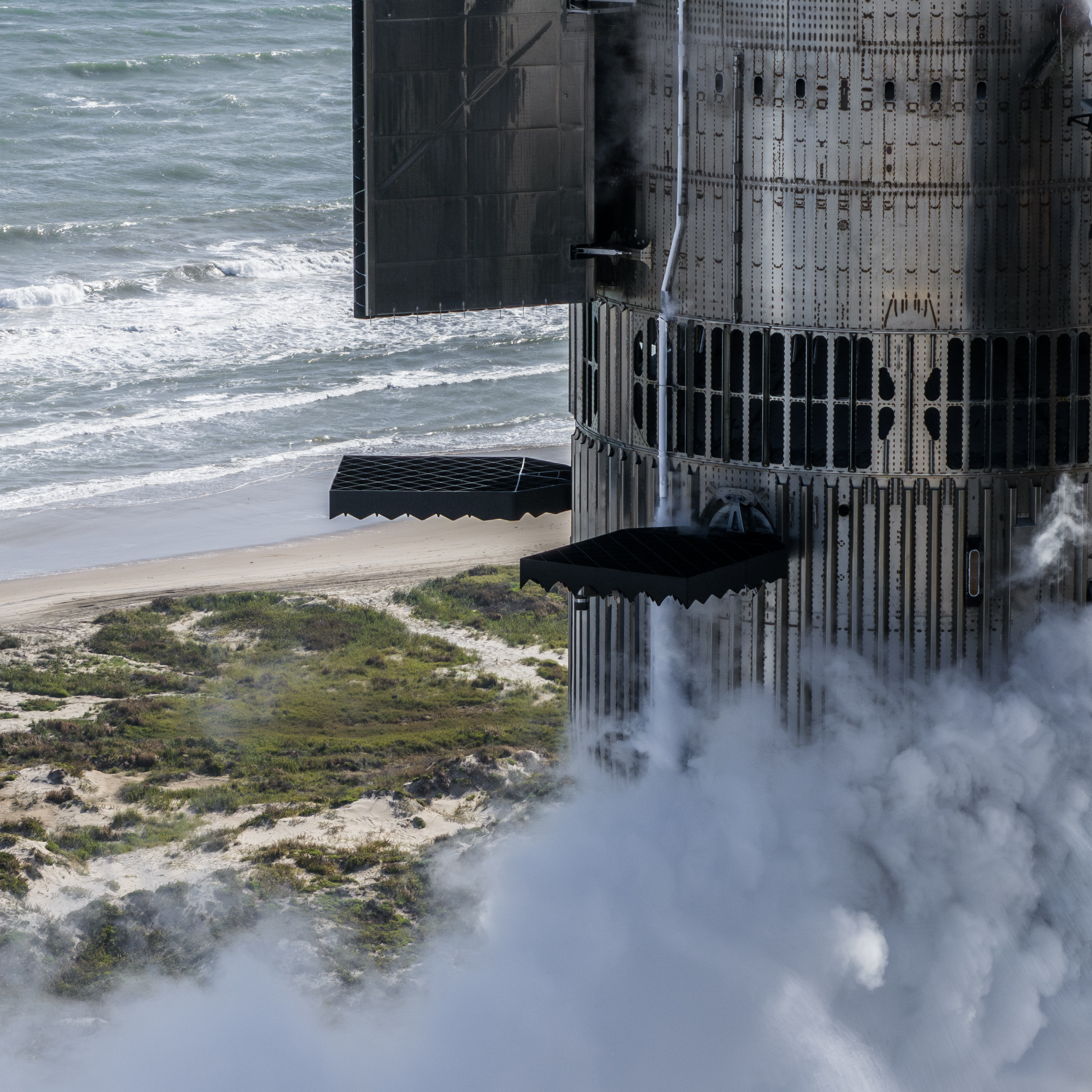 A tall chrome rocket stands next to a black tower, frosted in sections as sections are frosted white from super chilled fuel inside.