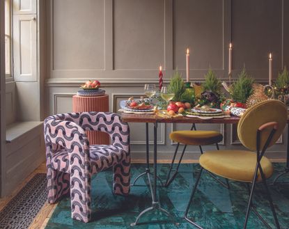 Christmas decorations with foliage and flowers, a table setting, fruits and glasses, a wood panelled room with a table and mismatched chairs.