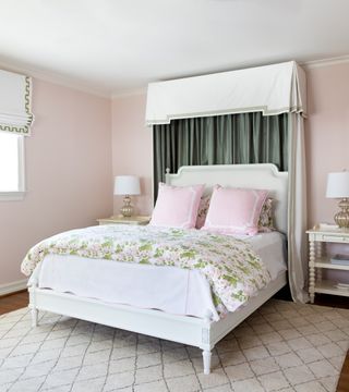 blush bedroom with green and white canopy, floral quilt and pillows, cream bedsides, patterned rug