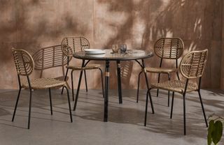 A bamboo-effect outdoor dining set on a patio with terracotta coloured walls