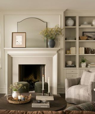 Cream living room with striped armchair, sage green ottomans and vases