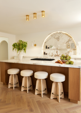 a modern kitchen with an arch above the sink filled in with marble that matches the kitchen island countertop