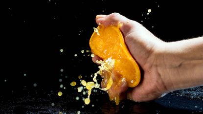 A person aggressively squeezing an orange