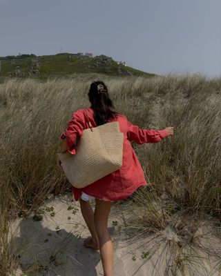 @_jessicaskye wearing a shirt and shorts and big raffia tote on the beach