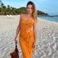 Sabina Socol on the beach wearing an orange dress