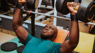 Man performs incline dumbbell bench press with heavy dumbbells in gym