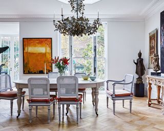 White dining room with antique dining chairs and wooden flooring