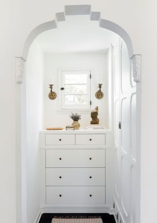 arched shaped alcove with white chest of drawers and white fitted wardrobes