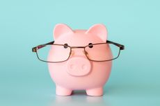 Piggy bank in the form of a pink pig with glasses on a light blue background.