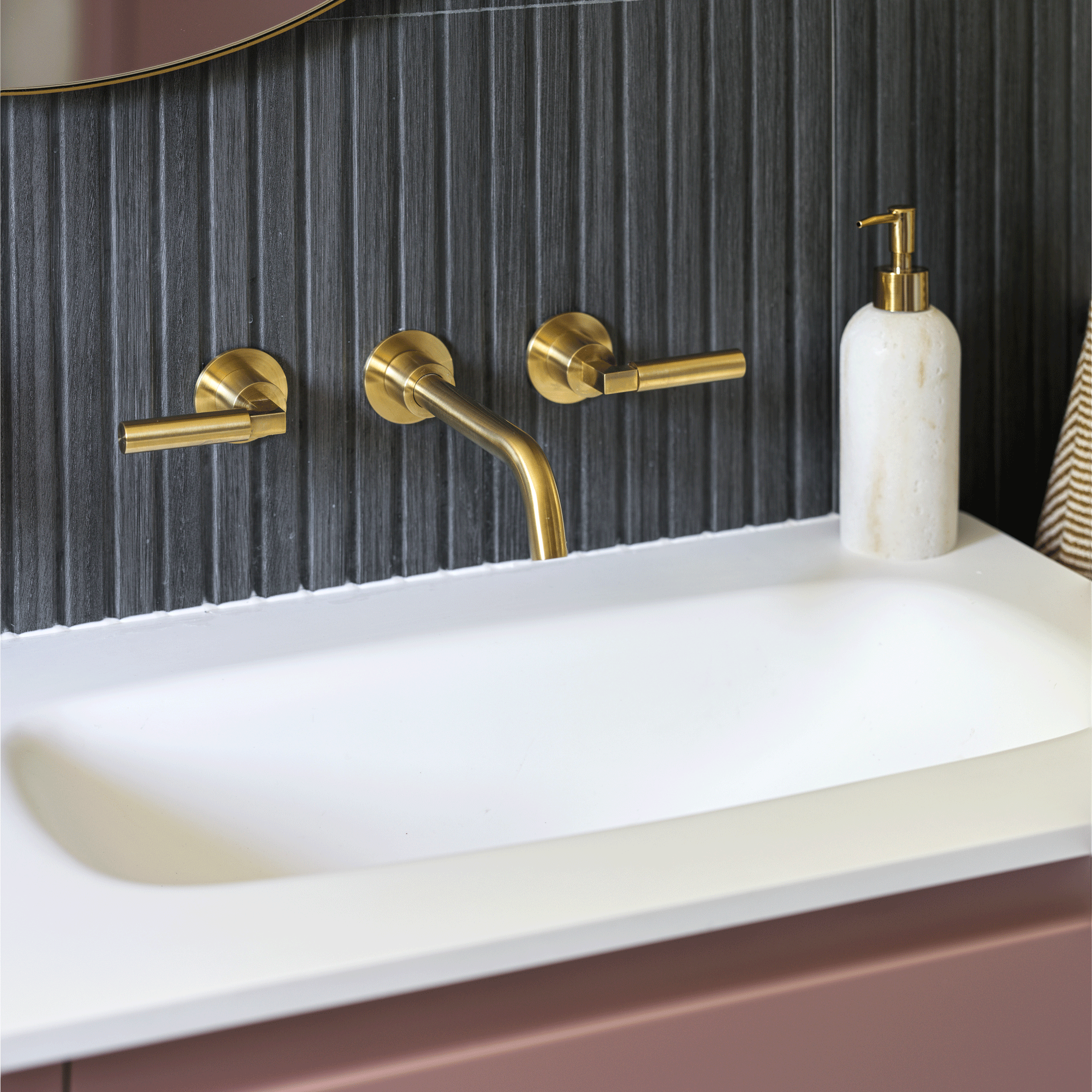 close up of a set of wall-hung taps in a bathroom with charcoal pencil wall tiles