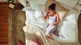 Pregnant woman looking at her phone in bed