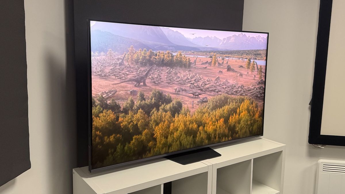 The 65-inch Hisense UR9 RGB Mini LED TV, photographed on a white, wooden unit. On the screen is a still from Netflix documentary, The Dinosaurs.