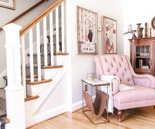 hall with pink armchair and stairs behind with wooden floor and wooden cabinet